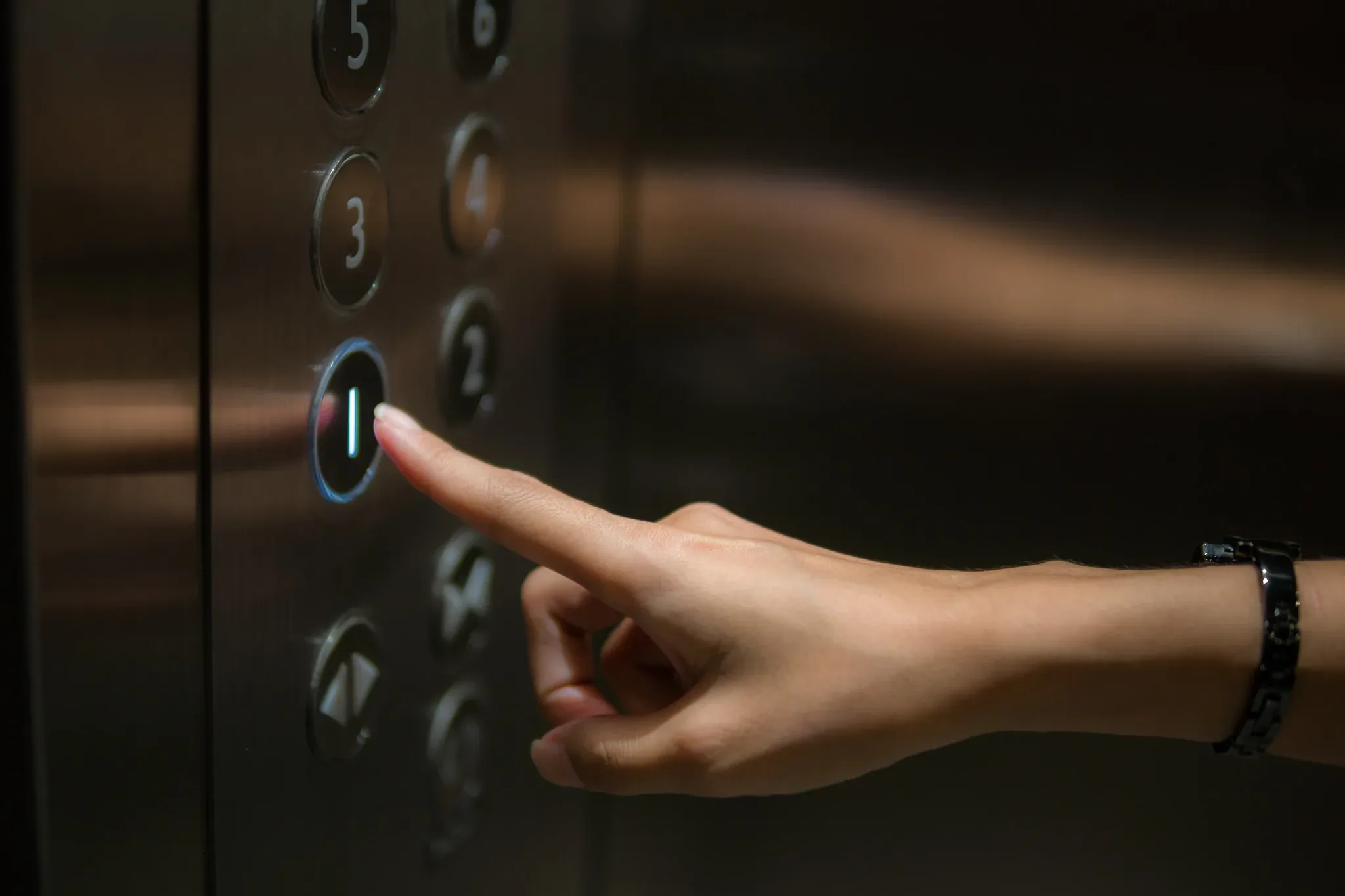 A person pressing the button on an elevator.